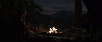Movie still from “Love and Monsters” (2020), directed by Michael Matthews – A man laying on the ground next to a fire pit; Extreme Wide shot, High angle