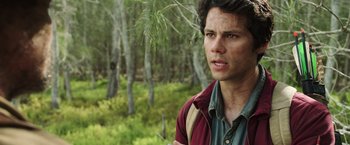 Movie still from “Love and Monsters” (2020), directed by Michael Matthews – A young man in a field with trees in the background; Close Up shot, Over the shoulder angle