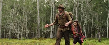 Movie still from “Love and Monsters” (2020), directed by Michael Matthews – A man and a child walking through a forest; Medium shot, Over the shoulder angle