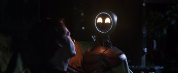 Movie still from “Love and Monsters” (2020), directed by Michael Matthews – A man looking into a mirror that is lit up with two eyes; Close Up shot, Over the shoulder angle