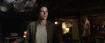 Movie still from “Love and Monsters” (2020), directed by Michael Matthews – A man standing in a dark room looking to his left; Medium shot, Low angle