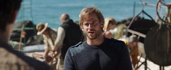 Movie still from “Love and Monsters” (2020), directed by Michael Matthews – A person wearing a sweater near a body of water; Close Up shot, Over the shoulder angle