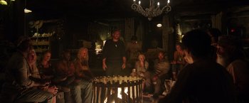 Movie still from “Love and Monsters” (2020), directed by Michael Matthews – A group of people sitting around a fire pit; Wide shot, High angle