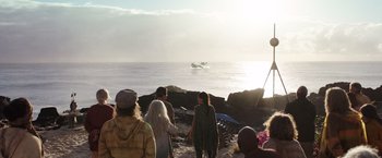 Movie still from “Love and Monsters” (2020), directed by Michael Matthews – A group of people standing on a beach watching a boat; Extreme Wide shot, High angle