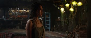 Movie still from “Love and Monsters” (2020), directed by Michael Matthews – A woman standing in a dark room looking to her left; Medium shot, Over the shoulder angle