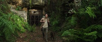 Movie still from “Love and Monsters” (2020), directed by Michael Matthews – A man and a dog are walking through the woods; Wide shot, Low angle