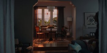 Movie still from “Love Hard” (2021), directed by Hernán Jiménez – A dining room table and chairs in a room with an open door; Extreme Wide shot, High angle