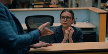 Movie still from “Love Hard” (2021), directed by Hernán Jiménez – A woman sitting in front of a man in a chair; Medium shot, Over the shoulder angle