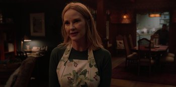 Movie still from “Love Hard” (2021), directed by Hernán Jiménez – A woman wearing an apron standing in front of a table; Close Up shot, Over the shoulder angle