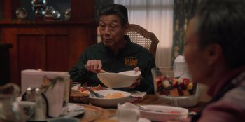 Movie still from “Love Hard” (2021), directed by Hernán Jiménez – A man sitting at a dinner table with a bowl of food; Medium shot, Over the shoulder angle