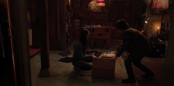Movie still from “Love Hard” (2021), directed by Hernán Jiménez – Two women in a room with a cardboard box; Medium shot, High angle