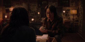 Movie still from “Love Hard” (2021), directed by Hernán Jiménez – Two people sitting at a table with a cup of coffee; Medium shot, Over the shoulder angle