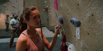 Movie still from “Love Hard” (2021), directed by Hernán Jiménez – A woman in a pink tank top is climbing a rock wall; Close Up shot, Low angle