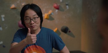 Movie still from “Love Hard” (2021), directed by Hernán Jiménez – A man giving a thumbs up in front of a climbing wall; Close Up shot, Low angle