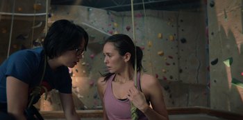 Movie still from “Love Hard” (2021), directed by Hernán Jiménez – A woman is talking to another woman in a gym; Medium shot, Low angle