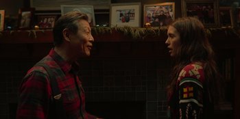 Movie still from “Love Hard” (2021), directed by Hernán Jiménez – A man and a woman talking in front of a fireplace; Medium shot, Over the shoulder angle