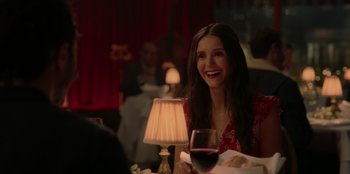 Movie still from “Love Hard” (2021), directed by Hernán Jiménez – A woman sitting at a table with a glass of red wine; Medium shot, Over the shoulder angle