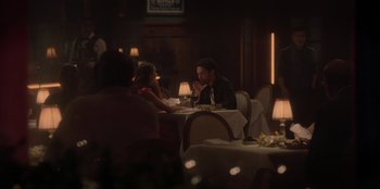 Movie still from “Love Hard” (2021), directed by Hernán Jiménez – A group of people sitting at a table in a restaurant; Wide shot, Over the shoulder angle
