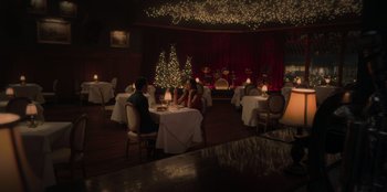 Movie still from “Love Hard” (2021), directed by Hernán Jiménez – Two people are sitting at a table in a restaurant; Extreme Wide shot, High angle