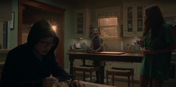 Movie still from “Love Hard” (2021), directed by Hernán Jiménez – Two people sitting at a table in a kitchen; Medium shot, Over the shoulder angle