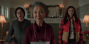 Movie still from “Love Hard” (2021), directed by Hernán Jiménez – A woman wearing a red sweater standing next to two other women; Close Up shot, Over the shoulder angle