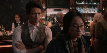 Movie still from “Love Hard” (2021), directed by Hernán Jiménez – A man and a woman standing next to each other in a bar; Medium shot, Over the shoulder angle
