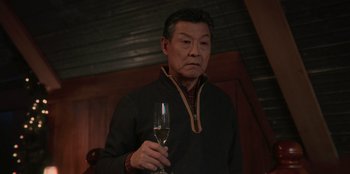 Movie still from “Love Hard” (2021), directed by Hernán Jiménez – An older man holding a glass of wine in his hand; Medium shot, Over the shoulder angle