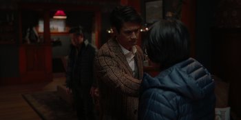 Movie still from “Love Hard” (2021), directed by Hernán Jiménez – A man standing next to a woman in a room; Medium shot, Over the shoulder angle