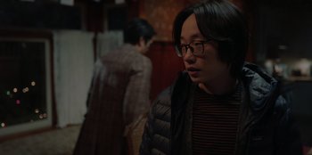 Movie still from “Love Hard” (2021), directed by Hernán Jiménez – A young man wearing glasses and a black jacket; Medium shot, Over the shoulder angle