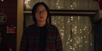Movie still from “Love Hard” (2021), directed by Hernán Jiménez – A man in a plaid shirt wearing glasses; Medium shot, Over the shoulder angle