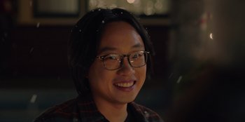 Movie still from “Love Hard” (2021), directed by Hernán Jiménez – A man with glasses smiling for the camera; Close Up shot, Over the shoulder angle