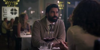 Movie still from “Love in the Villa” (2022), directed by Mark Steven Johnson – A man sitting at a table with a glass of wine; Close Up shot, Over the shoulder angle