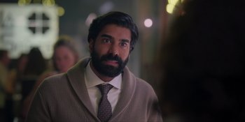 Movie still from “Love in the Villa” (2022), directed by Mark Steven Johnson – A man with a beard wearing a suit and tie; Close Up shot, Over the shoulder angle