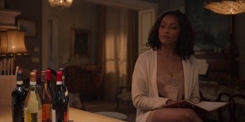 Movie still from “Love in the Villa” (2022), directed by Mark Steven Johnson – A woman sitting in front of a wine bottle; Medium shot, Over the shoulder angle