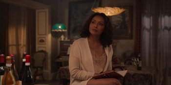 Movie still from “Love in the Villa” (2022), directed by Mark Steven Johnson – A woman sitting on a chair holding a book; Medium shot, Over the shoulder angle