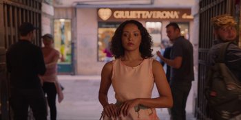 Movie still from “Love in the Villa” (2022), directed by Mark Steven Johnson – A woman standing in front of a store on the sidewalk; Medium shot, Over the shoulder angle