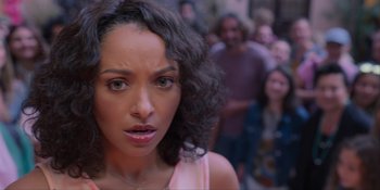 Movie still from “Love in the Villa” (2022), directed by Mark Steven Johnson – A person with a crowd of people in the background; Close Up shot, Over the shoulder angle