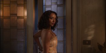 Movie still from “Love in the Villa” (2022), directed by Mark Steven Johnson – A woman standing in front of a glass door; Medium shot, Over the shoulder angle
