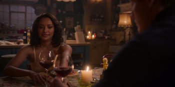Movie still from “Love in the Villa” (2022), directed by Mark Steven Johnson – A woman sitting at a table with a glass of red wine; Medium shot, Over the shoulder angle