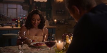 Movie still from “Love in the Villa” (2022), directed by Mark Steven Johnson – A woman sitting at a table with a plate of food; Medium shot, Over the shoulder angle