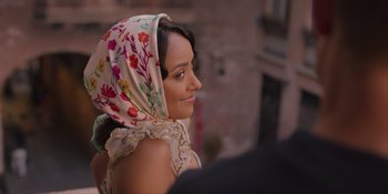 Movie still from “Love in the Villa” (2022), directed by Mark Steven Johnson – A woman wearing a floral headscarf looking to her left; Close Up shot, Over the shoulder angle