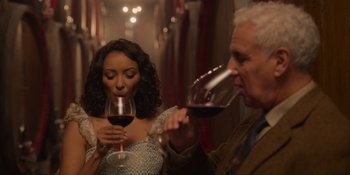 Movie still from “Love in the Villa” (2022), directed by Mark Steven Johnson – A woman and an older man are drinking wine; Medium shot, Over the shoulder angle