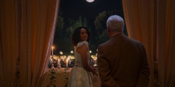 Movie still from “Love in the Villa” (2022), directed by Mark Steven Johnson – A man and a woman standing in front of candles; Medium shot, Over the shoulder angle