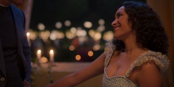 Movie still from “Love in the Villa” (2022), directed by Mark Steven Johnson – A beautiful woman smiling while standing next to a candle; Close Up shot, Over the shoulder angle