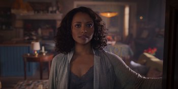 Movie still from “Love in the Villa” (2022), directed by Mark Steven Johnson – A woman with curly black hair standing in a room; Close Up shot, Over the shoulder angle