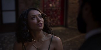 Movie still from “Love in the Villa” (2022), directed by Mark Steven Johnson – A beautiful woman with long curly brown hair wearing a black top; Close Up shot, Over the shoulder angle