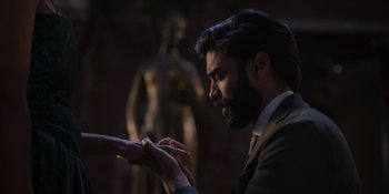 Movie still from “Love in the Villa” (2022), directed by Mark Steven Johnson – A man in a suit and tie holding something in his hand; Close Up shot, Over the shoulder angle