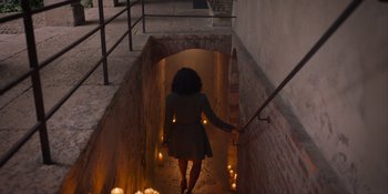 Movie still from “Love in the Villa” (2022), directed by Mark Steven Johnson – A woman walking down the stairs with candles; Wide shot, High angle
