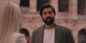 Movie still from “Love in the Villa” (2022), directed by Mark Steven Johnson – A man with a beard is standing in front of a brick wall; Close Up shot, Over the shoulder angle