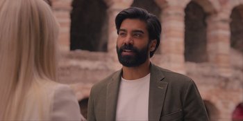 Movie still from “Love in the Villa” (2022), directed by Mark Steven Johnson – A man with a beard is standing in front of a brick wall; Close Up shot, Over the shoulder angle